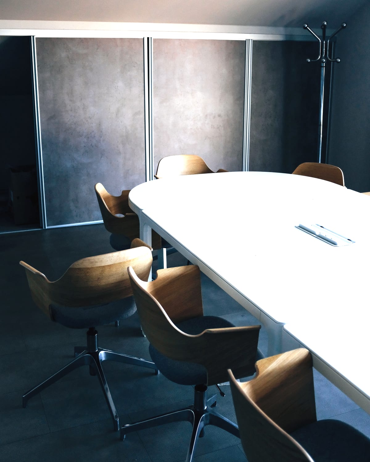 Un espace calme d'hôtel : une grande table blanche et des fauteuils en bois.